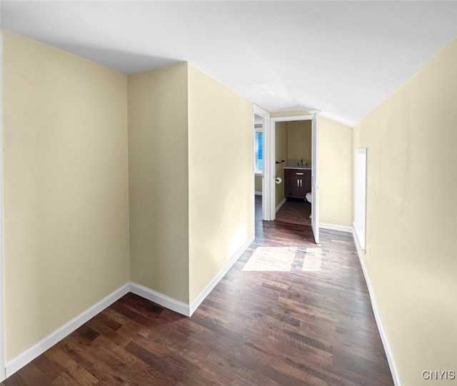 hallway featuring vaulted ceiling and dark hardwood / wood-style flooring