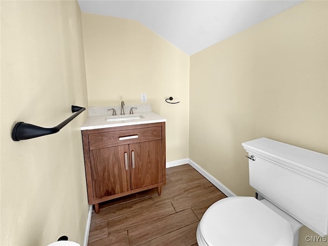 bathroom with vanity, toilet, lofted ceiling, and hardwood / wood-style floors