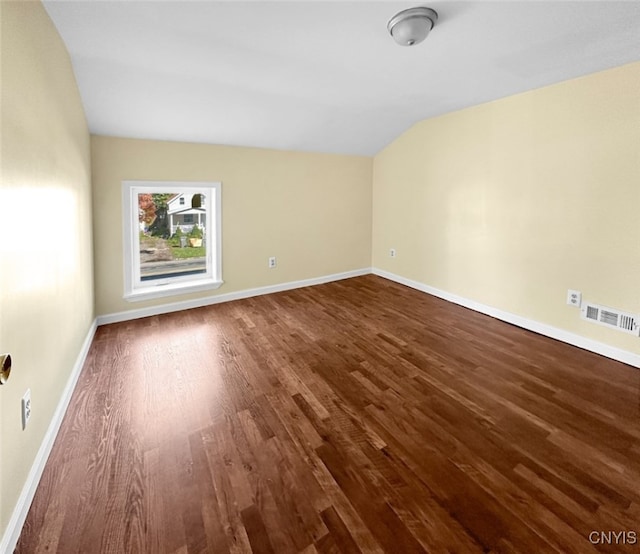 spare room featuring vaulted ceiling and hardwood / wood-style flooring