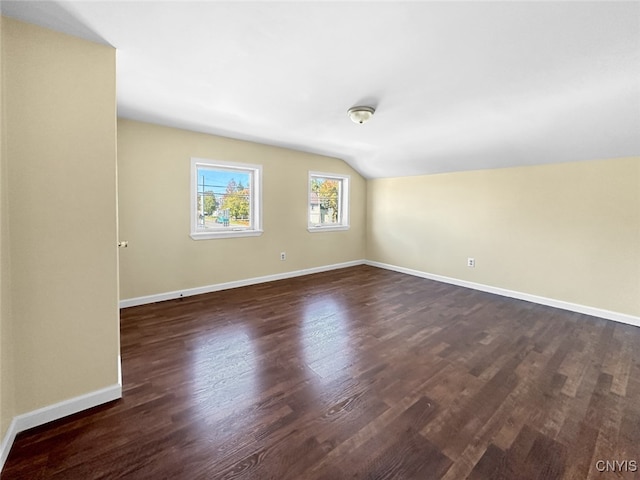 unfurnished room featuring vaulted ceiling and dark hardwood / wood-style flooring