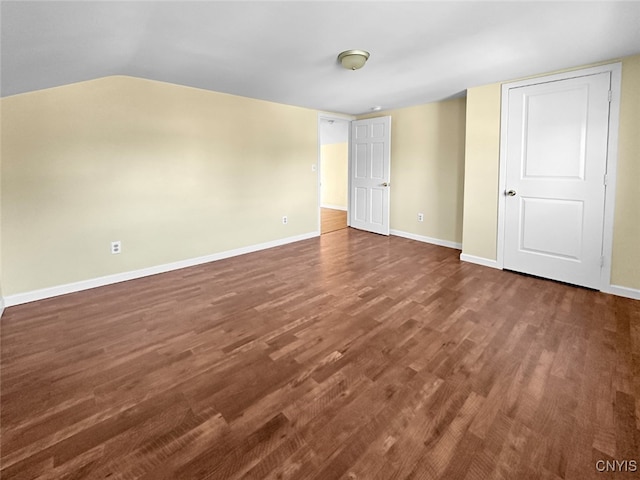 empty room featuring vaulted ceiling and dark hardwood / wood-style flooring