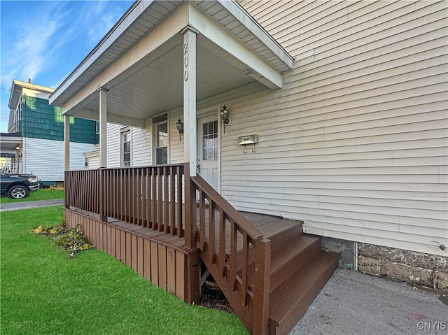 doorway to property with covered porch and a lawn