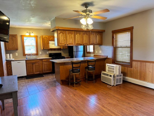 kitchen featuring a breakfast bar area, dark hardwood / wood-style floors, white appliances, and ceiling fan