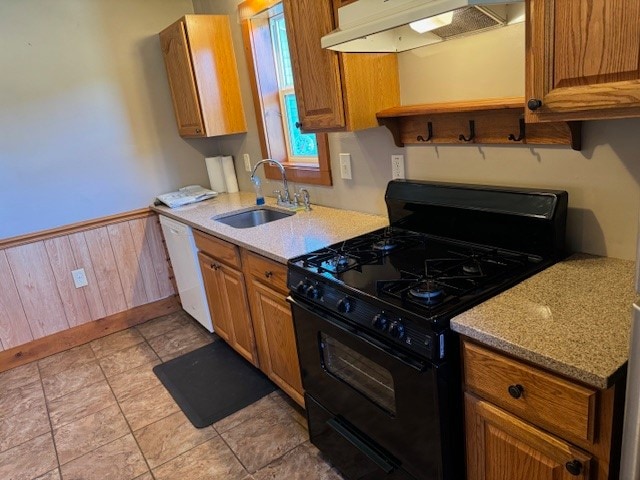 kitchen featuring wood walls, sink, dishwasher, black gas range, and range hood