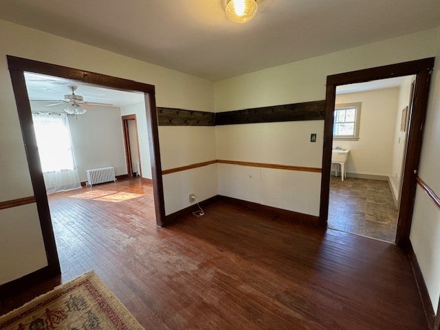 spare room featuring dark hardwood / wood-style floors, a healthy amount of sunlight, radiator, and ceiling fan