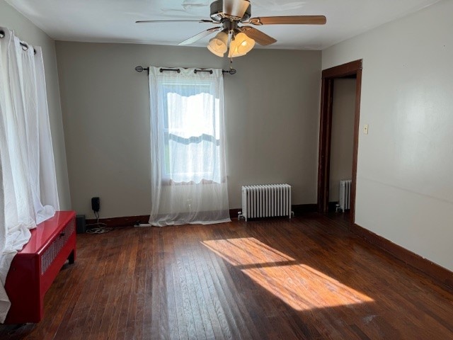 spare room featuring ceiling fan, radiator heating unit, and dark hardwood / wood-style floors