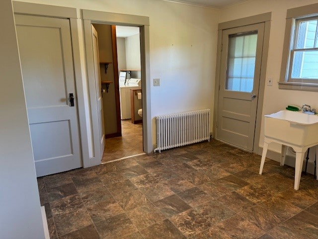 doorway to outside with radiator heating unit and washer / clothes dryer