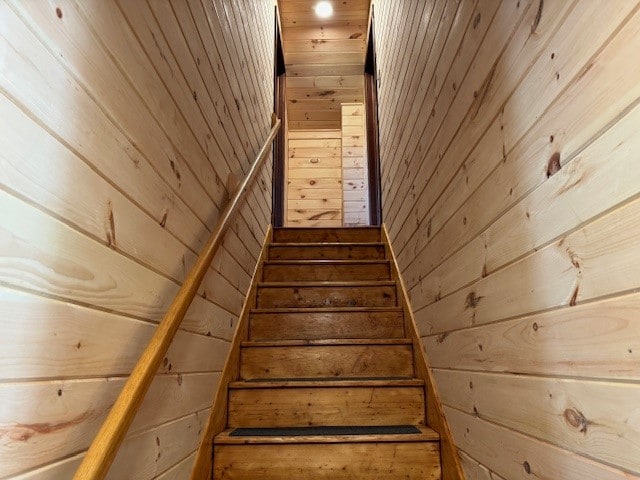 staircase with wood walls and wooden ceiling