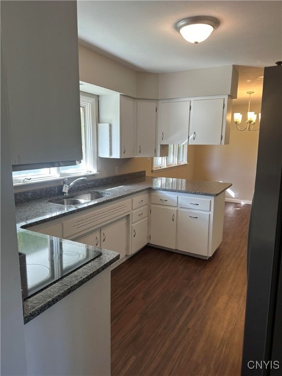 kitchen featuring kitchen peninsula, sink, a notable chandelier, white cabinets, and dark hardwood / wood-style flooring