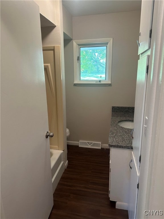 bathroom with vanity, a bath, hardwood / wood-style flooring, and toilet