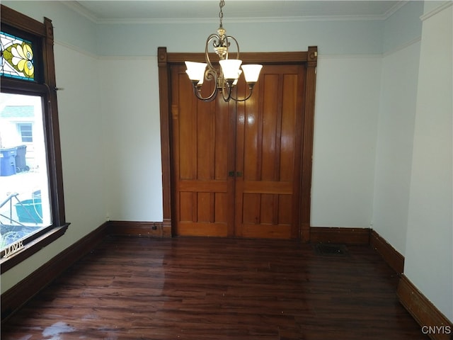 empty room featuring a healthy amount of sunlight, ornamental molding, and dark hardwood / wood-style flooring