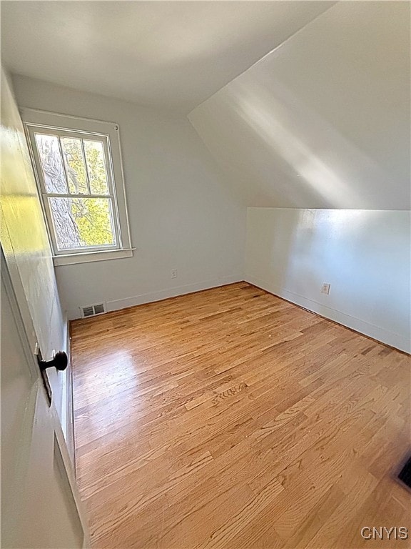 additional living space featuring lofted ceiling and light hardwood / wood-style floors