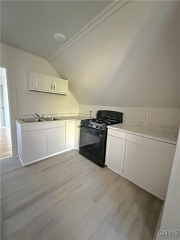 kitchen featuring sink, white cabinetry, black gas range, lofted ceiling, and light hardwood / wood-style flooring