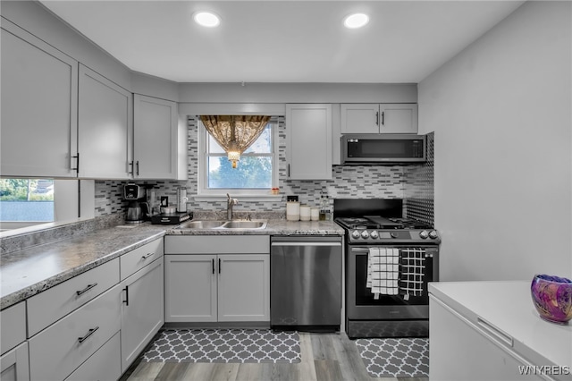 kitchen featuring light hardwood / wood-style floors, appliances with stainless steel finishes, sink, and backsplash