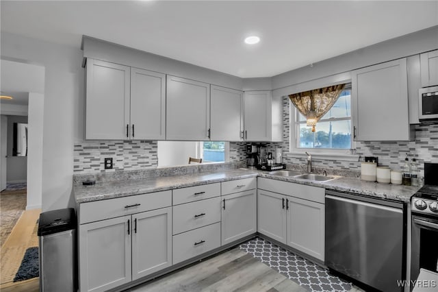 kitchen featuring backsplash, appliances with stainless steel finishes, light hardwood / wood-style flooring, plenty of natural light, and sink