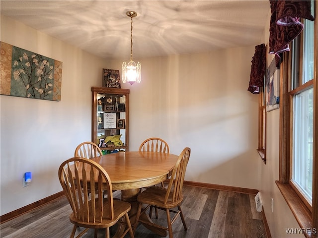 dining room featuring dark wood-type flooring, a notable chandelier, and a healthy amount of sunlight