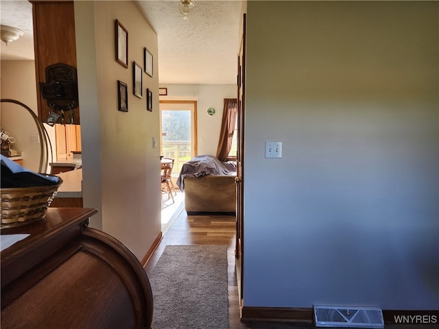 hall with a textured ceiling and hardwood / wood-style flooring