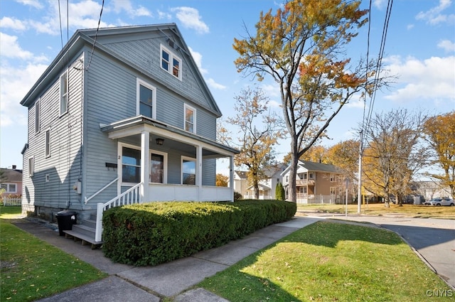 view of side of home featuring covered porch and a yard