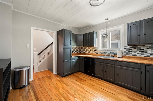 kitchen featuring sink, light hardwood / wood-style floors, decorative light fixtures, and black dishwasher