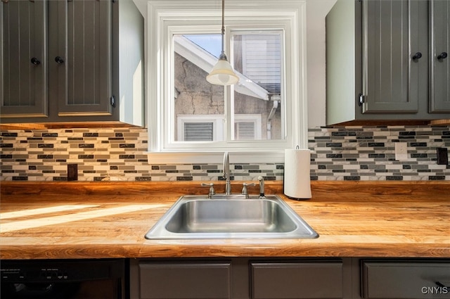 kitchen with wooden counters, tasteful backsplash, hanging light fixtures, and sink