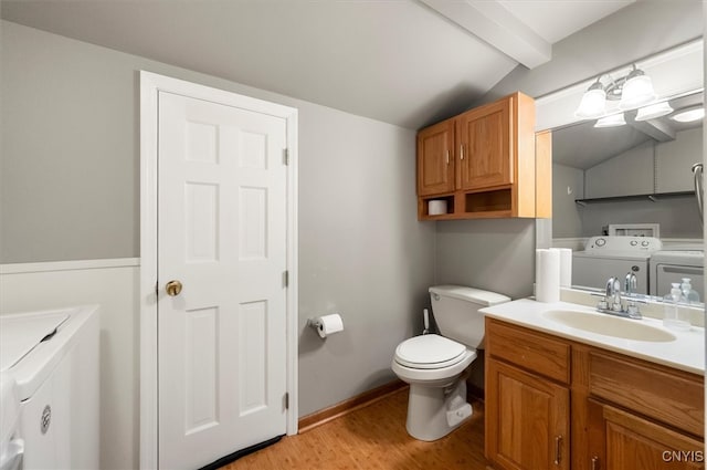 bathroom featuring washing machine and clothes dryer, vaulted ceiling with beams, hardwood / wood-style floors, toilet, and vanity