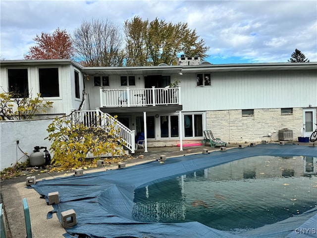 back of house with central AC unit, a covered pool, and a patio area