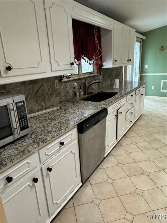 kitchen with light stone counters, white cabinetry, appliances with stainless steel finishes, sink, and decorative backsplash