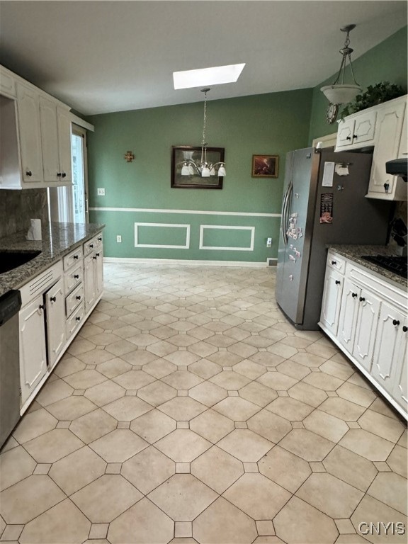 kitchen with pendant lighting, a skylight, white cabinetry, appliances with stainless steel finishes, and dark stone countertops