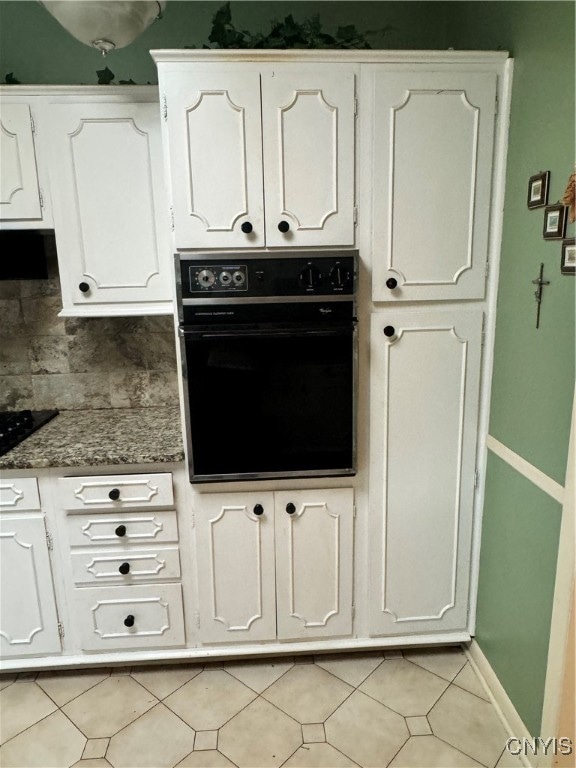 kitchen with white cabinets, light tile patterned floors, black appliances, and decorative backsplash