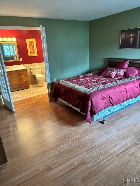 bedroom with hardwood / wood-style flooring and ensuite bath