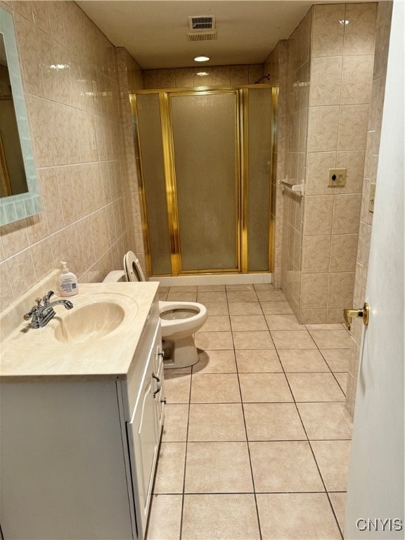 bathroom with a shower with shower door, vanity, toilet, and tile walls