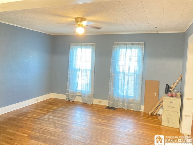 spare room with hardwood / wood-style floors, crown molding, and ceiling fan