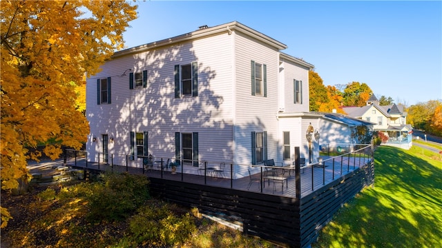 rear view of house with a wooden deck and a lawn