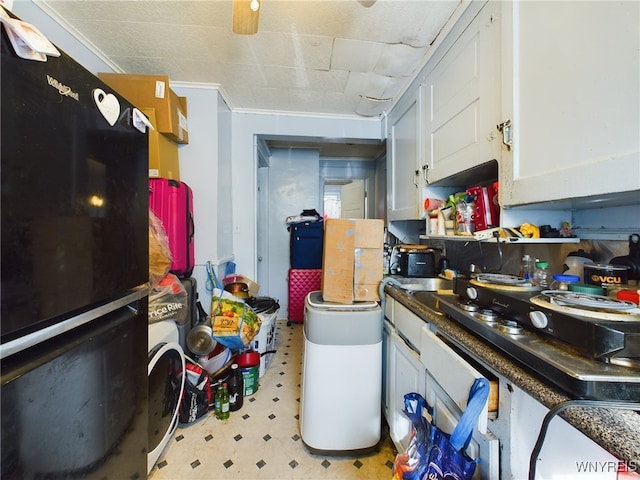 kitchen featuring crown molding, black refrigerator, and white cabinets