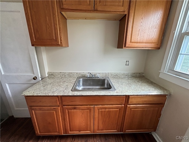 kitchen featuring sink, light stone counters, and dark hardwood / wood-style floors