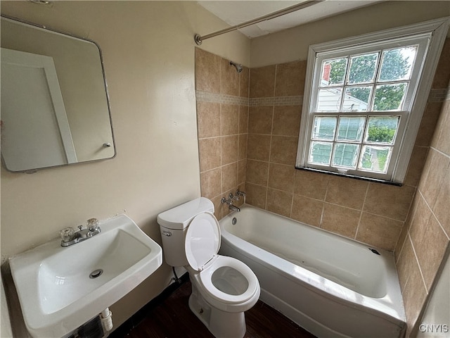 full bathroom featuring toilet, sink, plenty of natural light, and tiled shower / bath