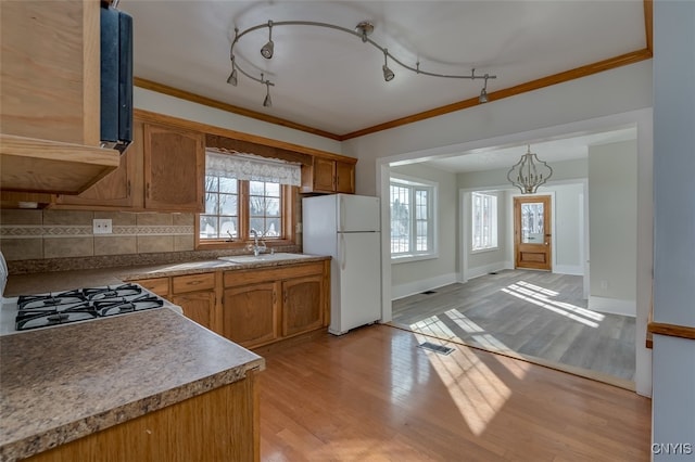 kitchen featuring hanging light fixtures, backsplash, light hardwood / wood-style flooring, sink, and white refrigerator