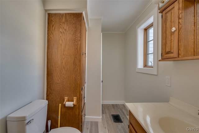 bathroom featuring toilet, ornamental molding, vanity, and wood-type flooring