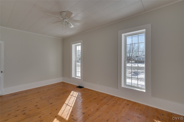 empty room featuring ornamental molding, light wood-type flooring, and ceiling fan