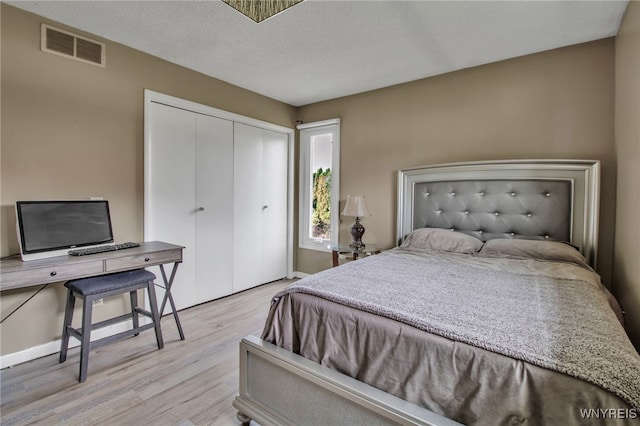 bedroom featuring a closet, a textured ceiling, and light wood-type flooring