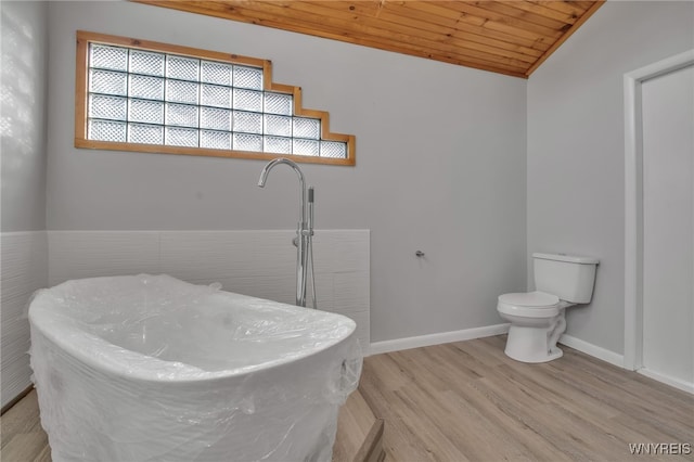 bathroom featuring lofted ceiling, hardwood / wood-style flooring, toilet, wooden ceiling, and a bathing tub