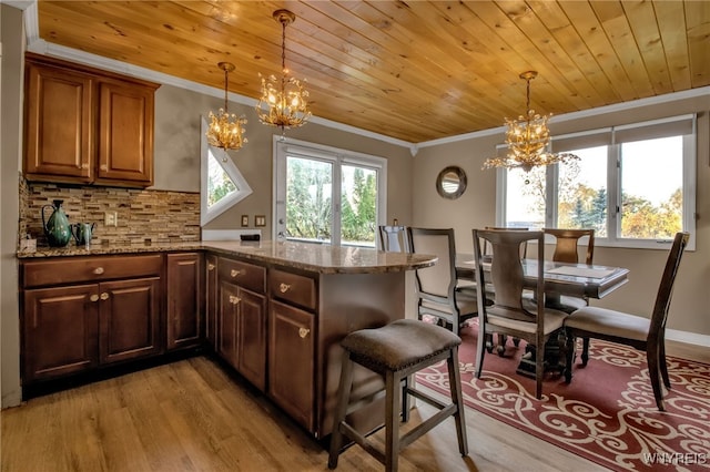 kitchen with ornamental molding, stone countertops, light wood-type flooring, and a healthy amount of sunlight