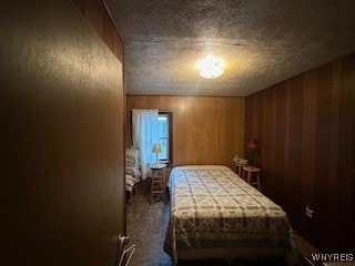 bedroom featuring a textured ceiling and wooden walls