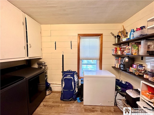 clothes washing area with light hardwood / wood-style floors, a textured ceiling, cabinets, and independent washer and dryer