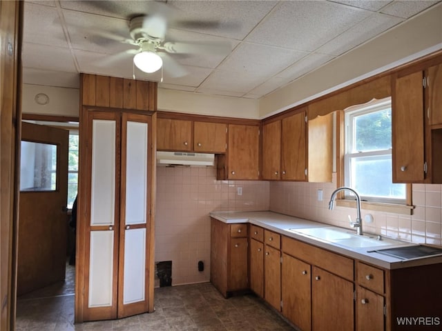 kitchen featuring dark tile patterned flooring, sink, a drop ceiling, backsplash, and ceiling fan