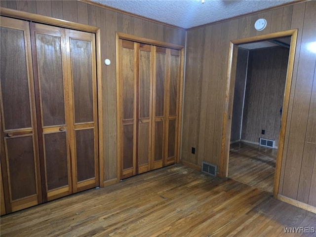 interior space featuring wood walls, a textured ceiling, and dark hardwood / wood-style flooring