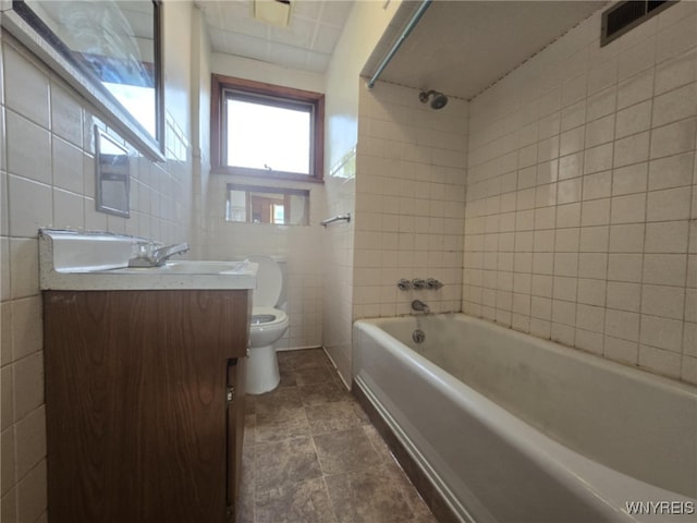 full bathroom featuring vanity, toilet, tile walls, and bathing tub / shower combination