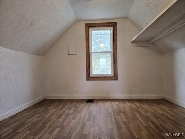 additional living space with a textured ceiling, lofted ceiling, and dark hardwood / wood-style floors