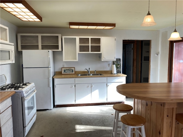 kitchen featuring pendant lighting, white appliances, white cabinets, a kitchen breakfast bar, and sink