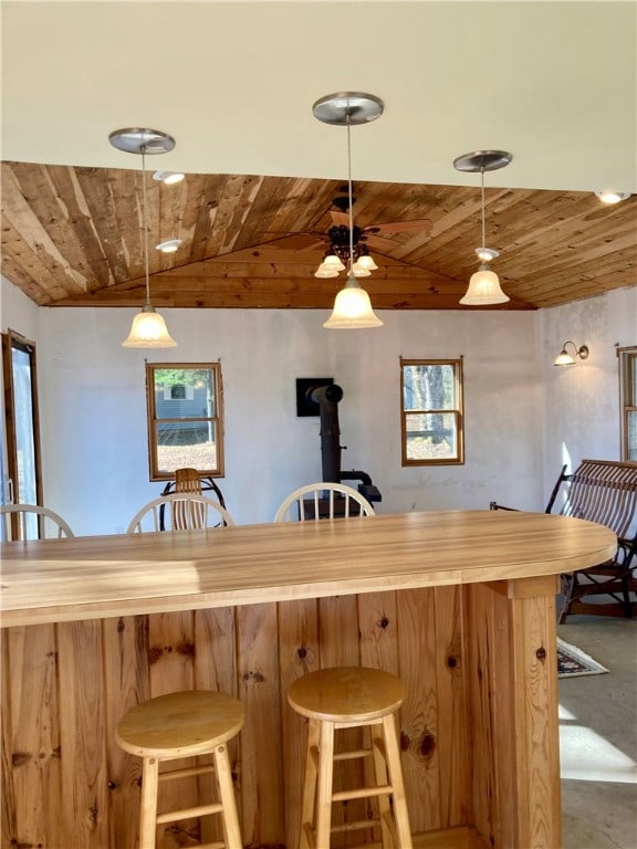 bar with carpet flooring, a wood stove, decorative light fixtures, and lofted ceiling